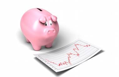 piggy bank next to a chart of a volatile financial statistics 