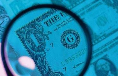 Magnifying glass inspecting US dollar bills