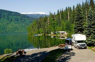 an rv parked next to a lake in a valley