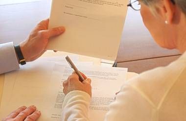 Close-up of woman signing legal documents at a table