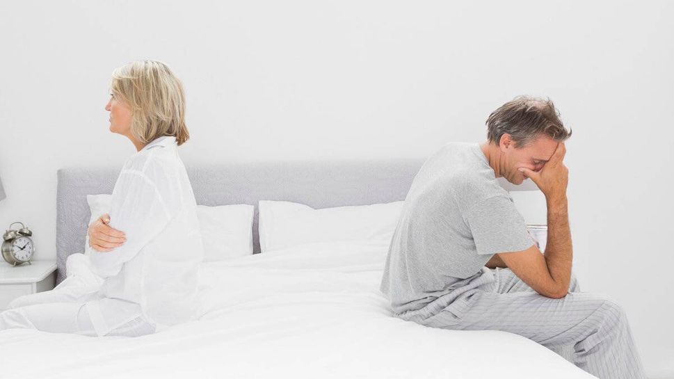 Couple sitting on opposite sides of bed