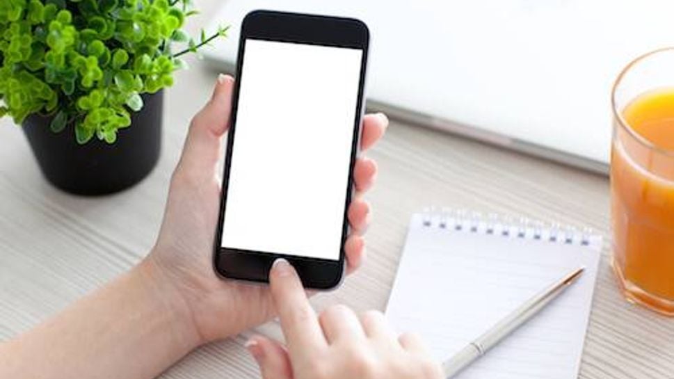 Women hand holding the phone with isolated screen above the desk