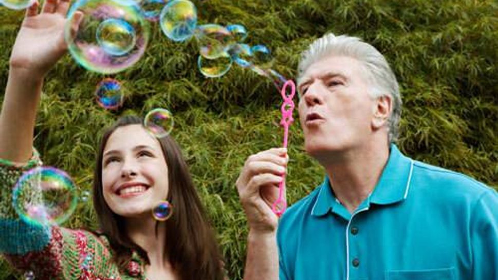 A grandfather and granddaughter blowing bubbles