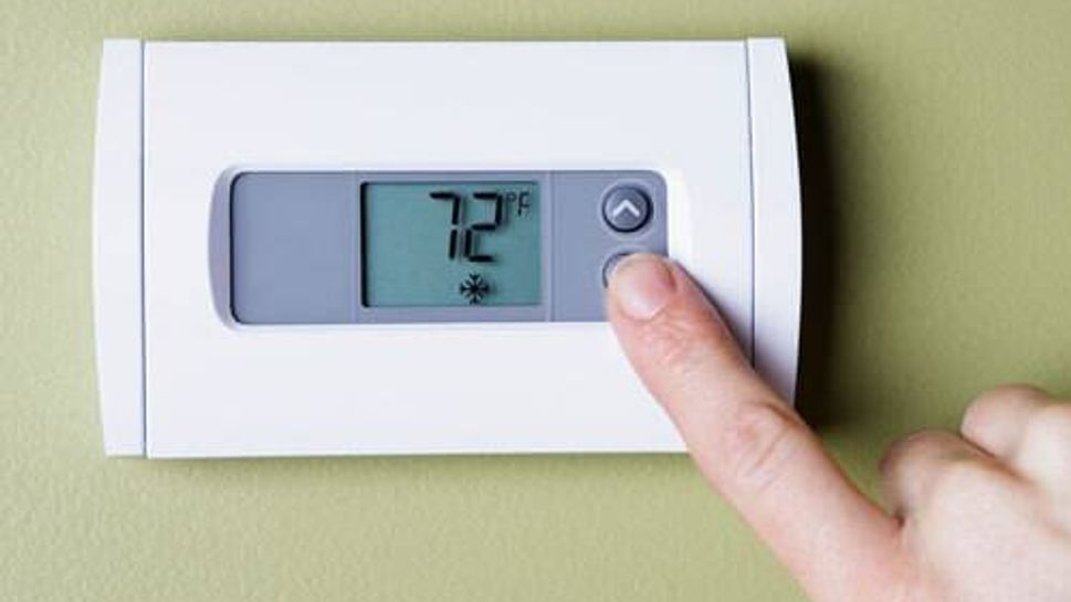 A person setting a thermostat