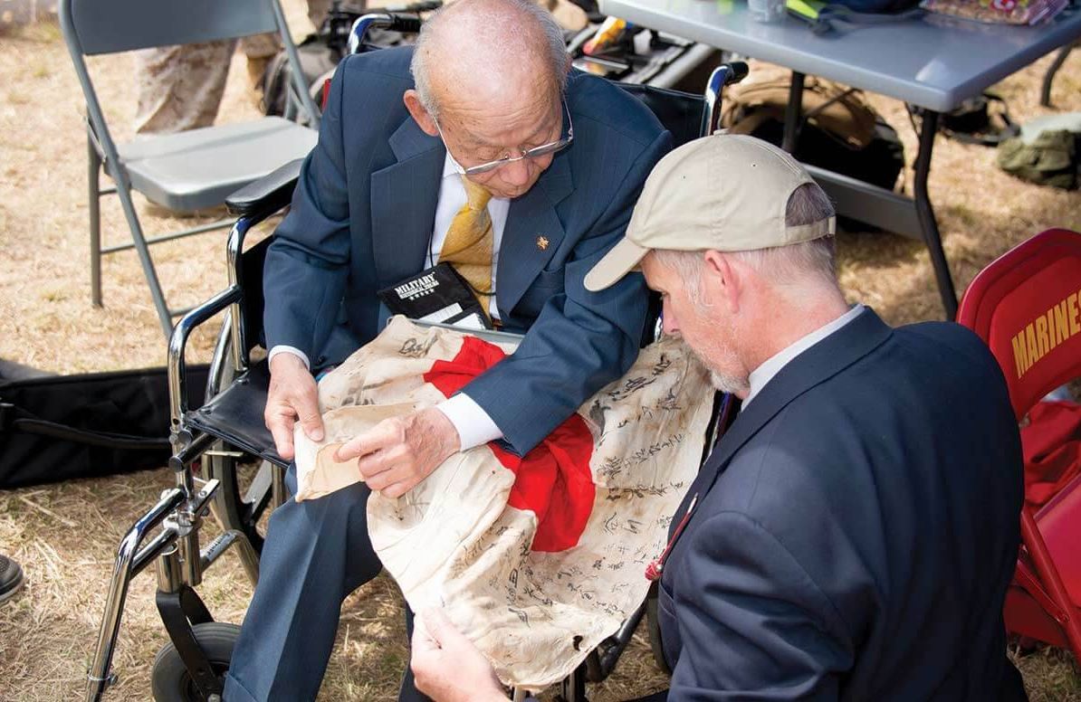 Japanese veteran Tsuruji Akikusa (left), with Dan King (right), author of “A Tomb Called Iwo Jima,” holding a Japanese flag that had been brought back to the U.S. as a souvenir during WWll.