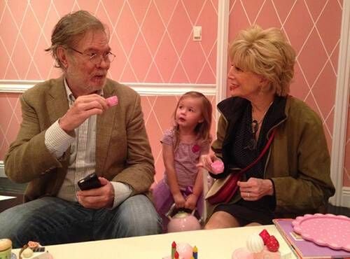 Lesley and her husband having a tea party with their granddaughter