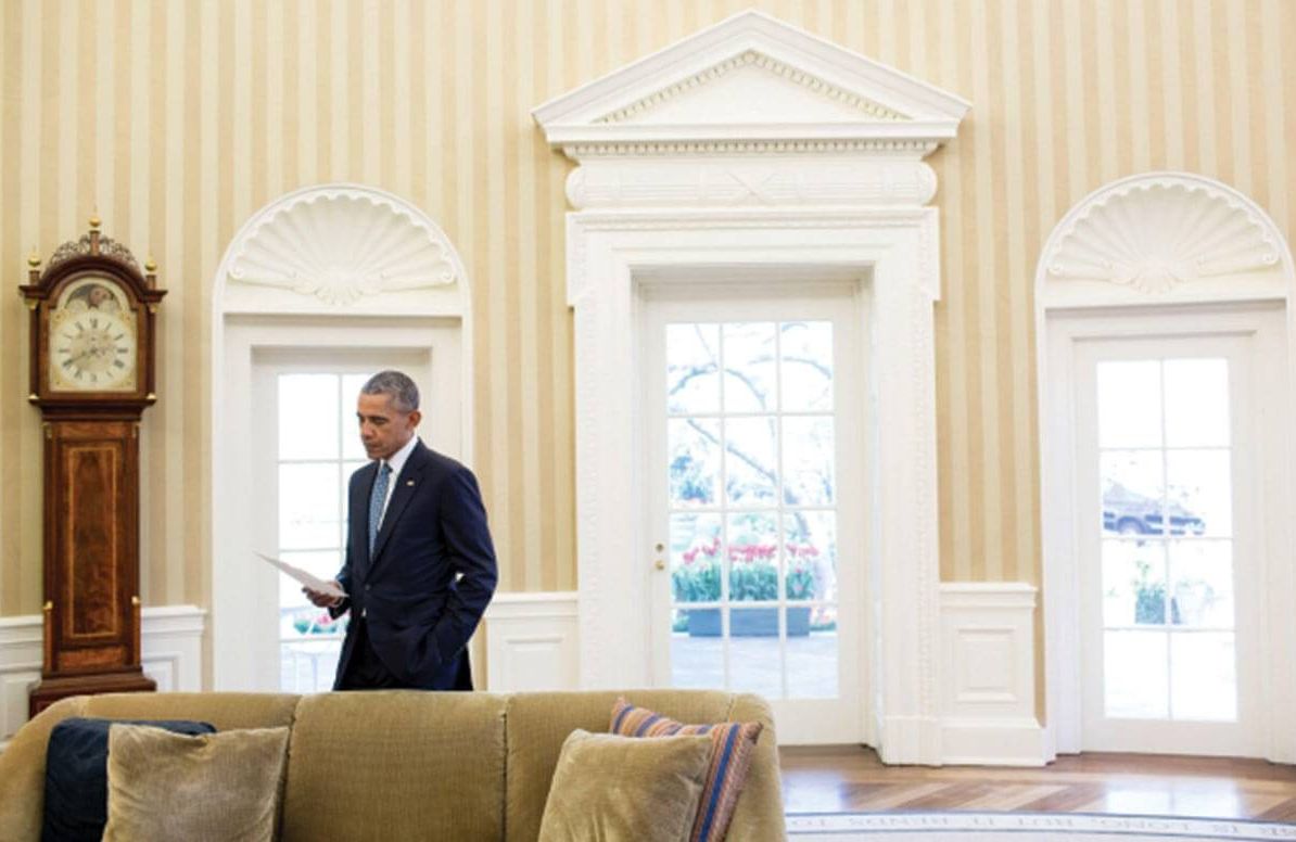 President Barack Obama looks over paperwork between meetings in the Oval Office, April 6, 2016.