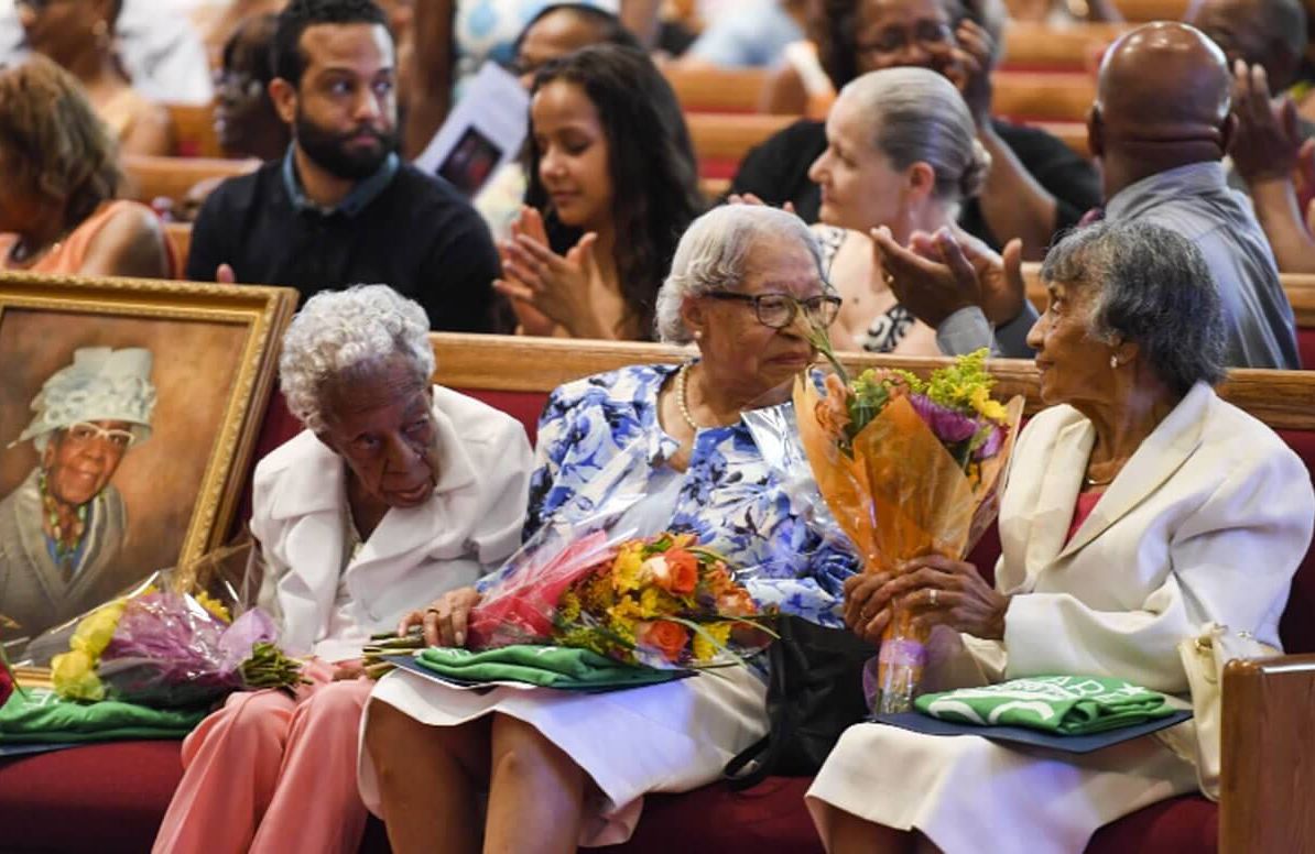 Ruth Chatman Hammett, Gladys Ware Butler and Bernice Grimes Underwood receive flowers during their 100th birthday celebration at Washington’s Zion Baptist Church on June 18. A portrait of their friend Leona Barnes, who died last month, is beside them.