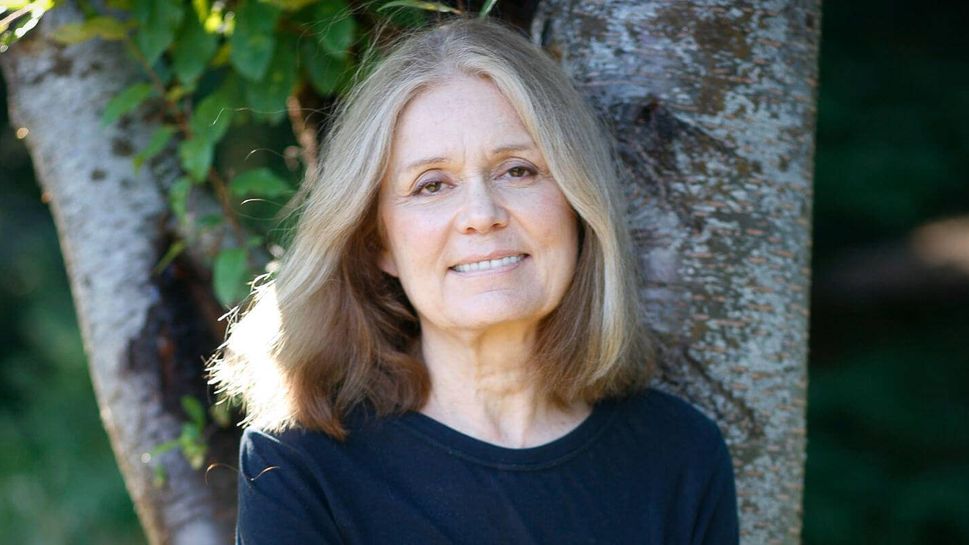 Gloria Steinem leaning against a tree