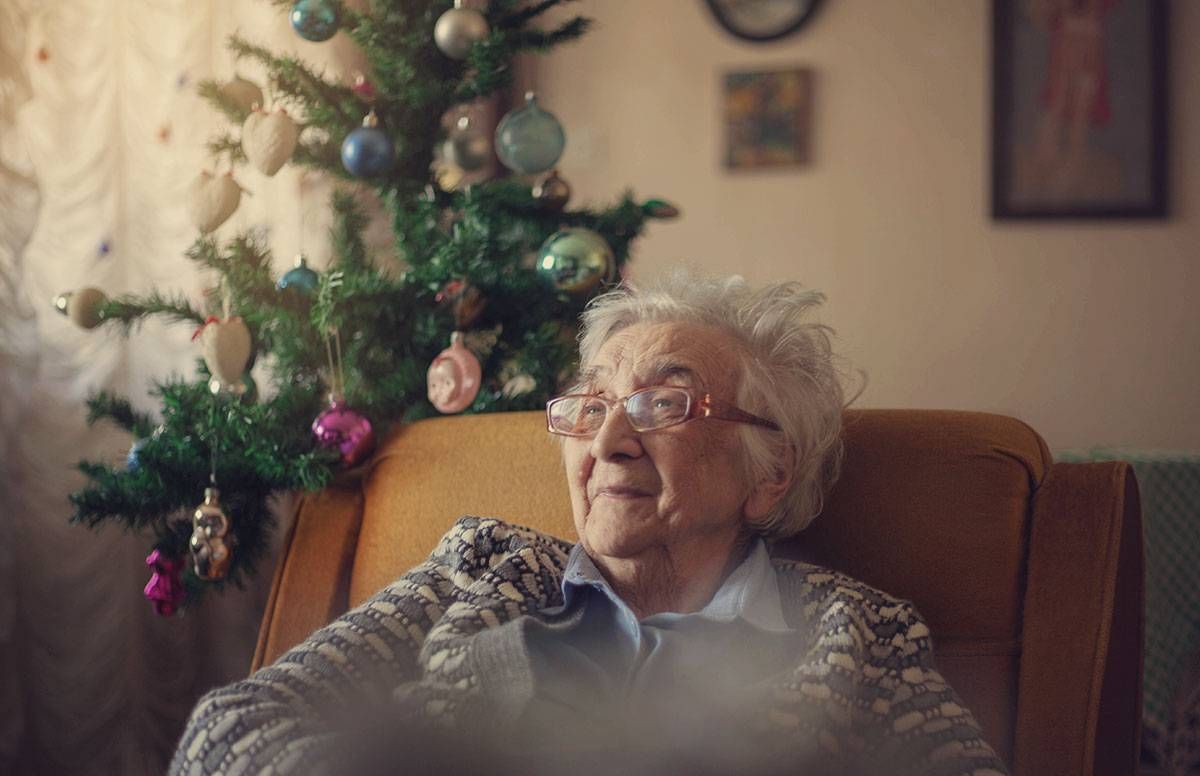 elderly woman sitting near a Christmas tree
