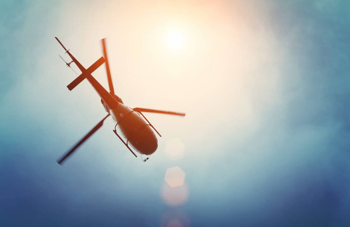 Helicopter flying in the blue sky with sun
