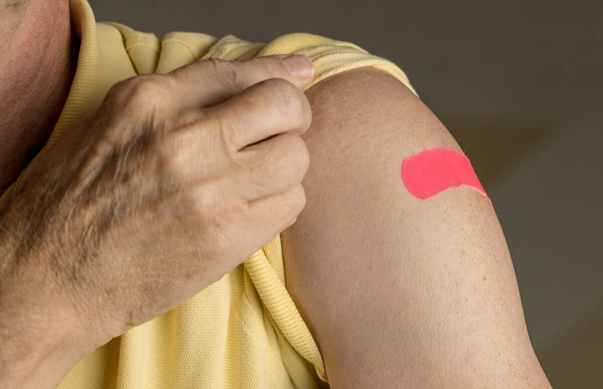 Senior man holding up shirt after flu injection