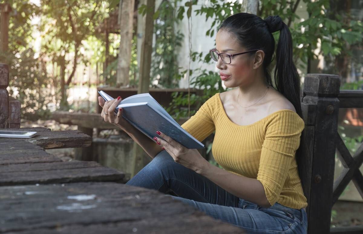 woman sitting in her home garden reading a book