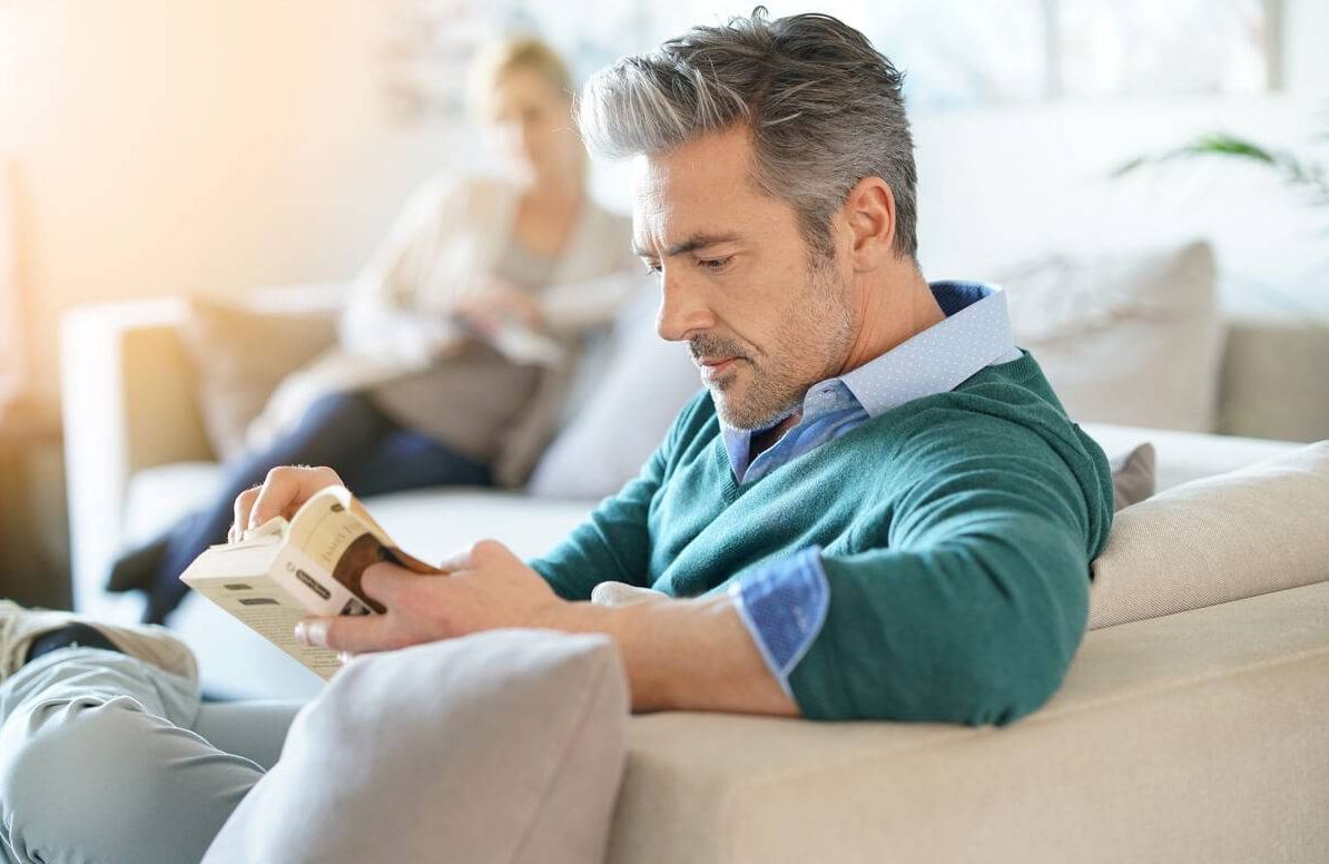 Couple at home reading book, man in foreground