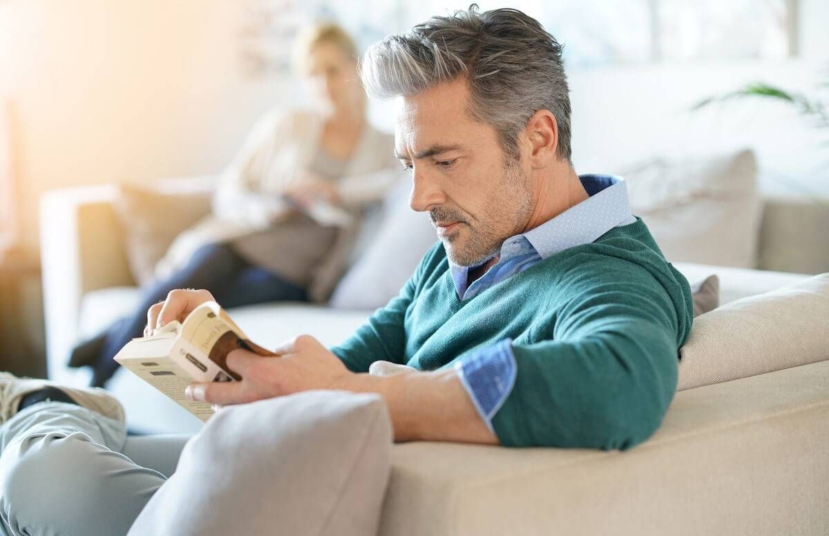 Couple at home reading book, man in foreground