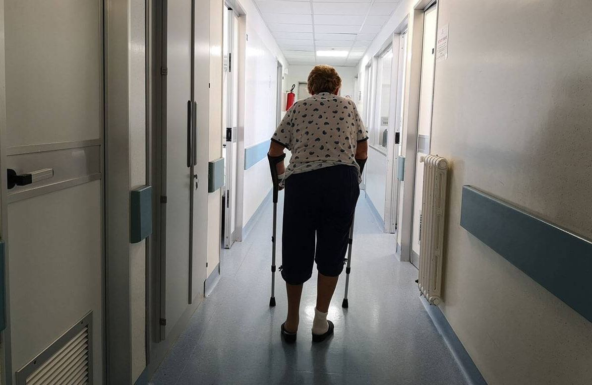 woman using a walker while walking down a hospital hallway