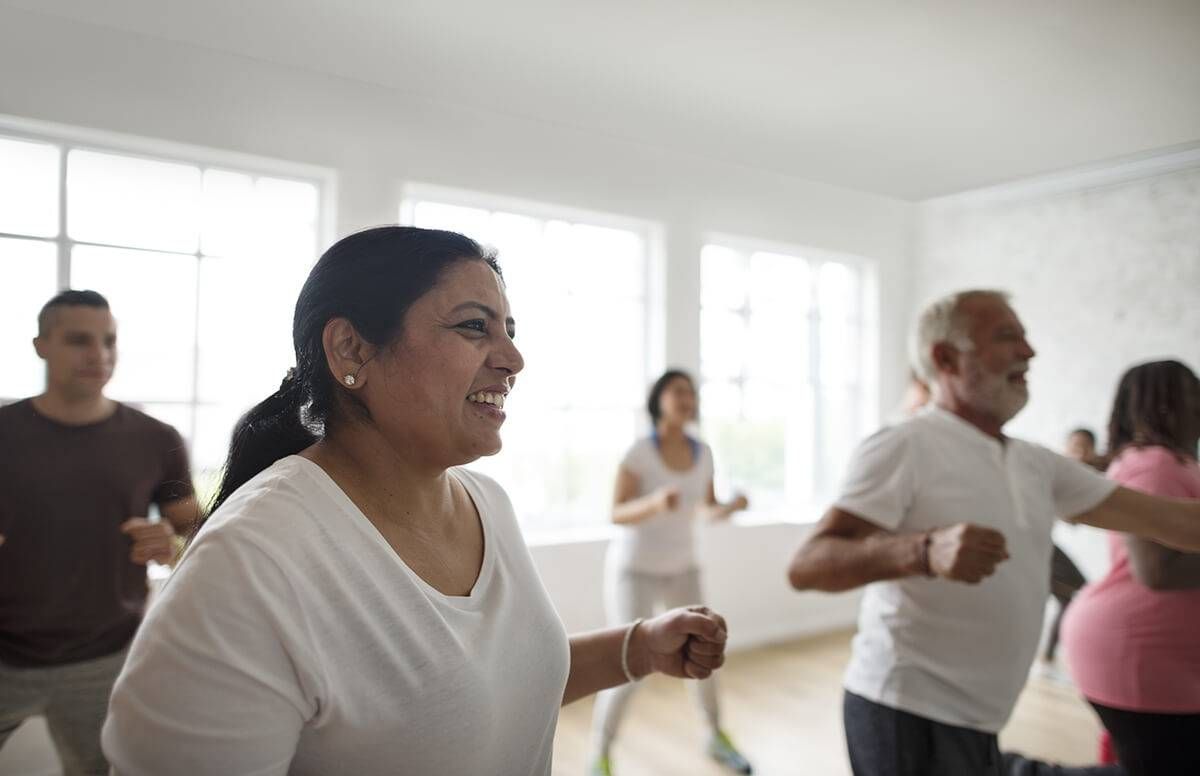 group of men and women dance in sync in a fitness classroom