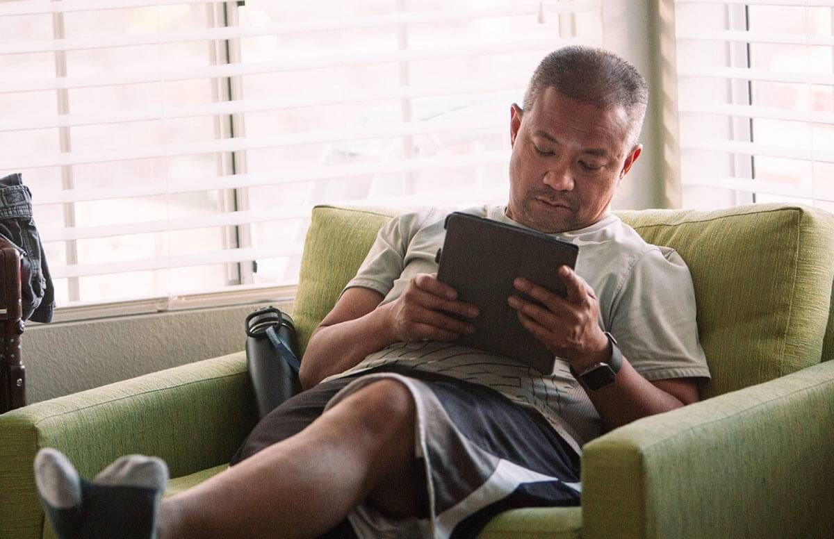 Man resting on a chair with his legs up, using a tablet device