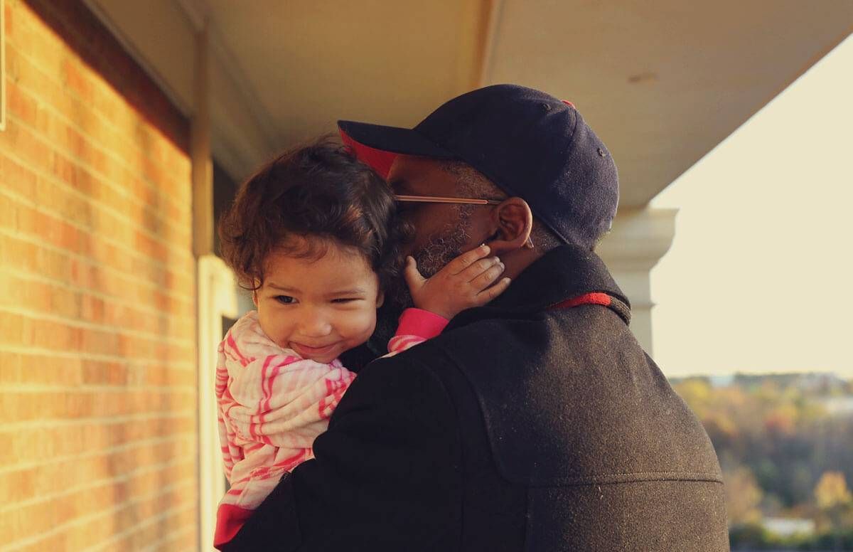 Older gentleman holding and hugging toddler child