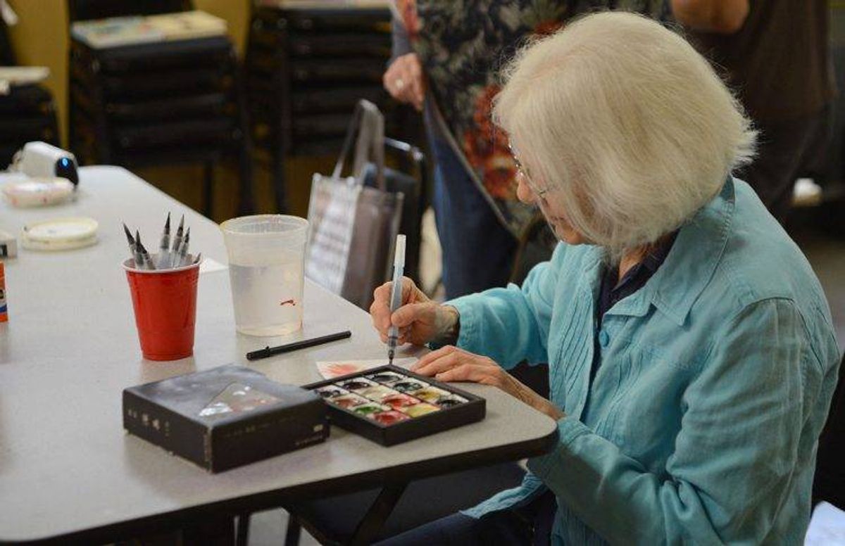 Margaret Cogelow works on a self-portrait using a Japanese watercolor set