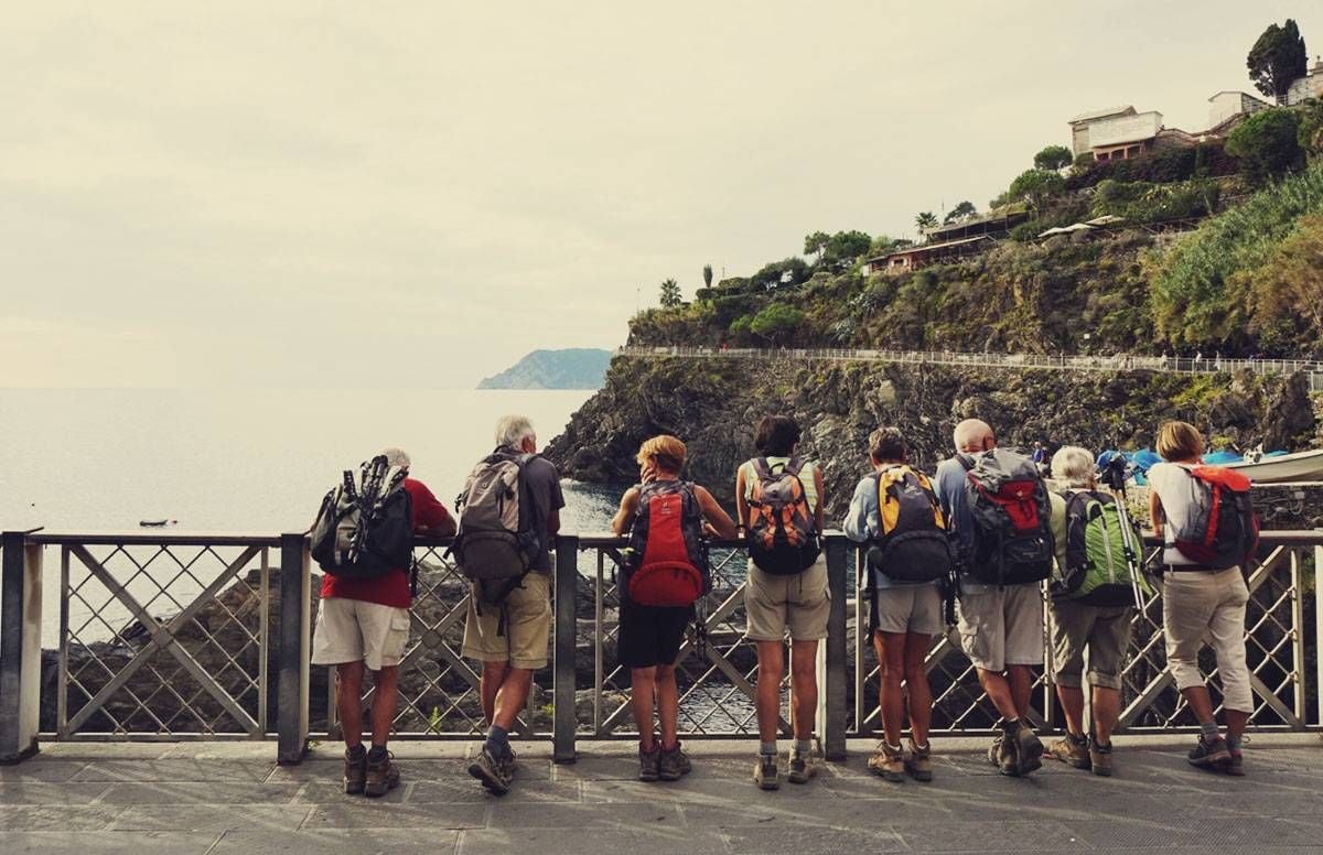 A group of people in middle age looking off a scenic point near water and a mountain