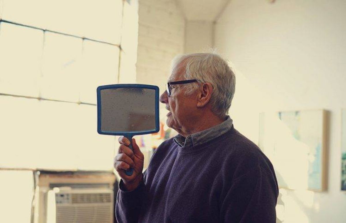 artist James Wrayge holding up the hand mirror he uses in his work