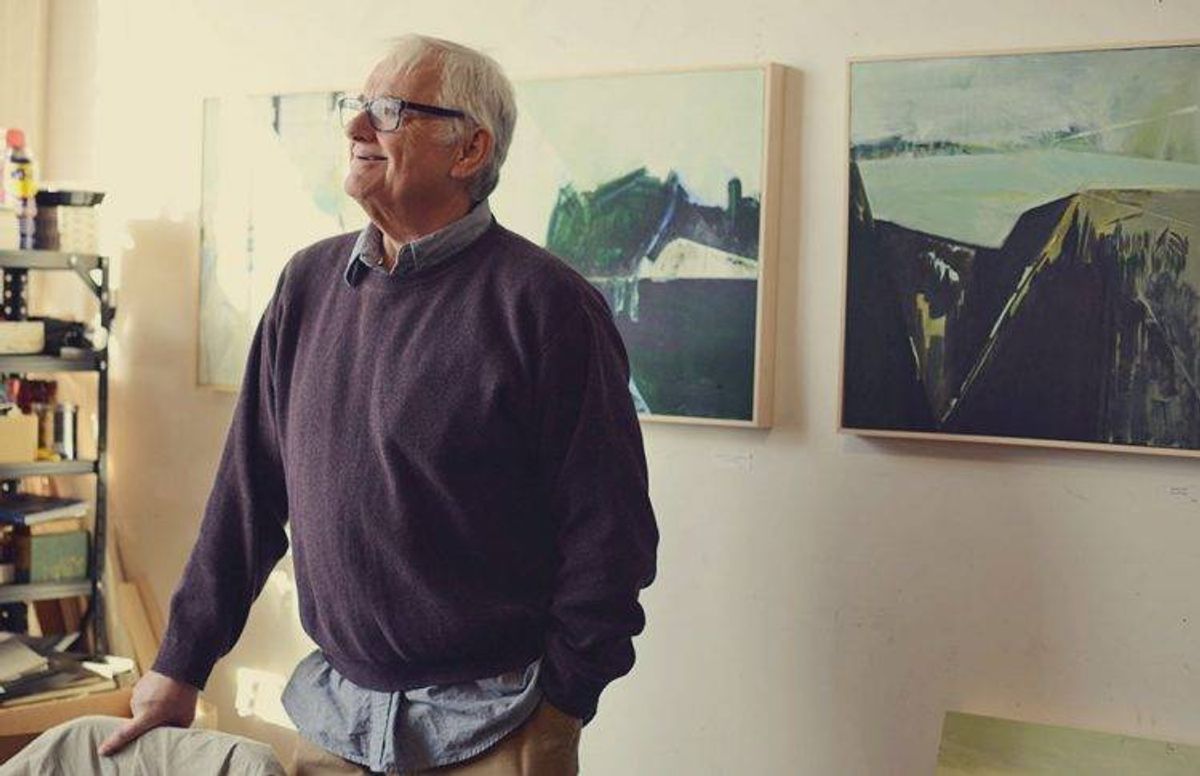 artist James Wrayge stands next to several of his paintings in his Minneapolis studio