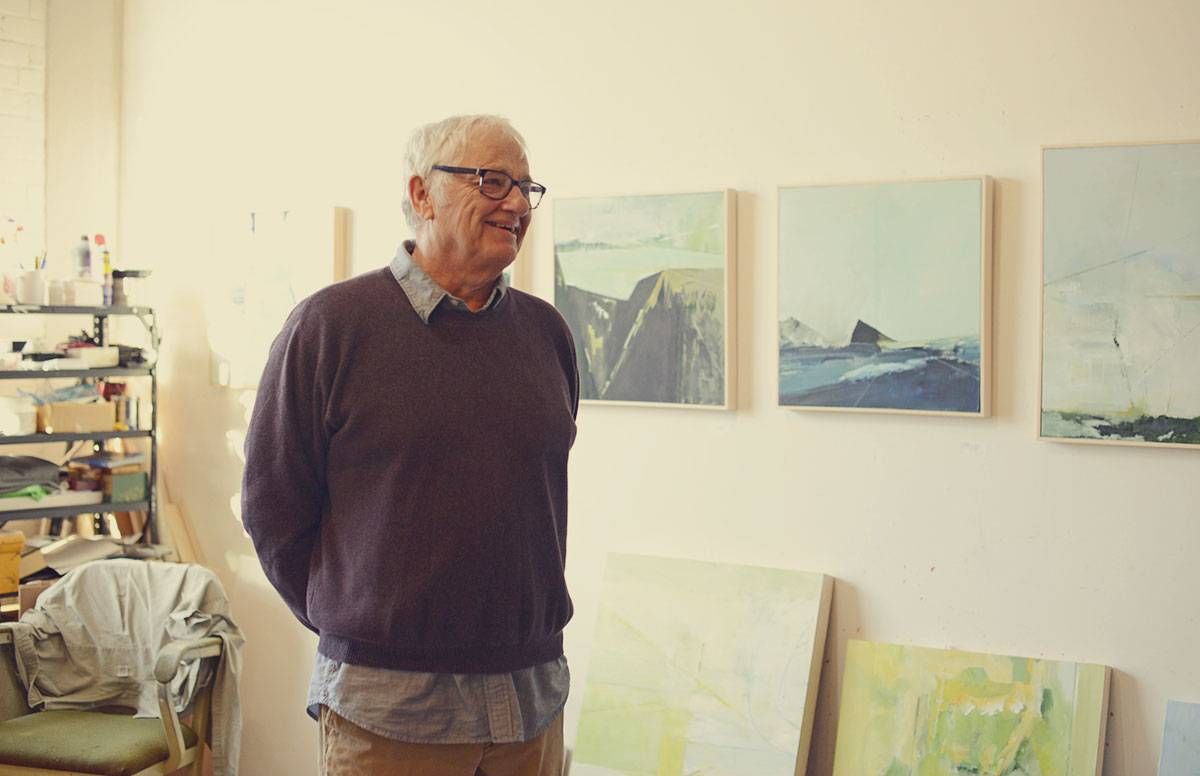 Artist James Wrayge poses near some of his paintings