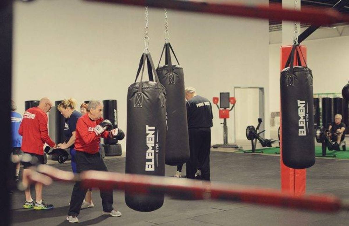 Student Jim Benson (foreground) practices different types of punches on a heavy bag while other students in the class work on other exercises.