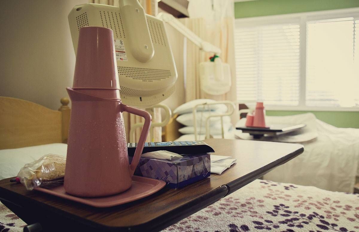 A nursing home room with two beds and a tray with a pitcher of water