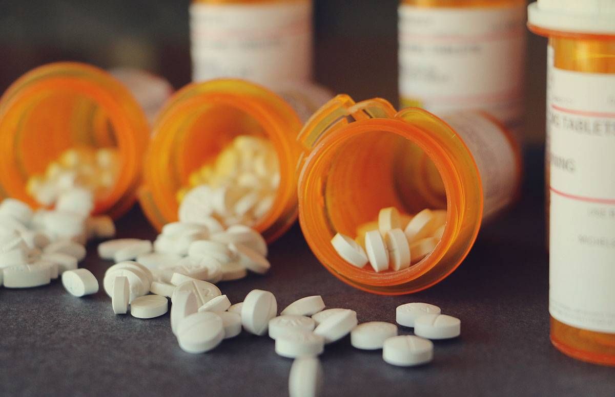 pill bottles opened, with pills spilling out onto the table