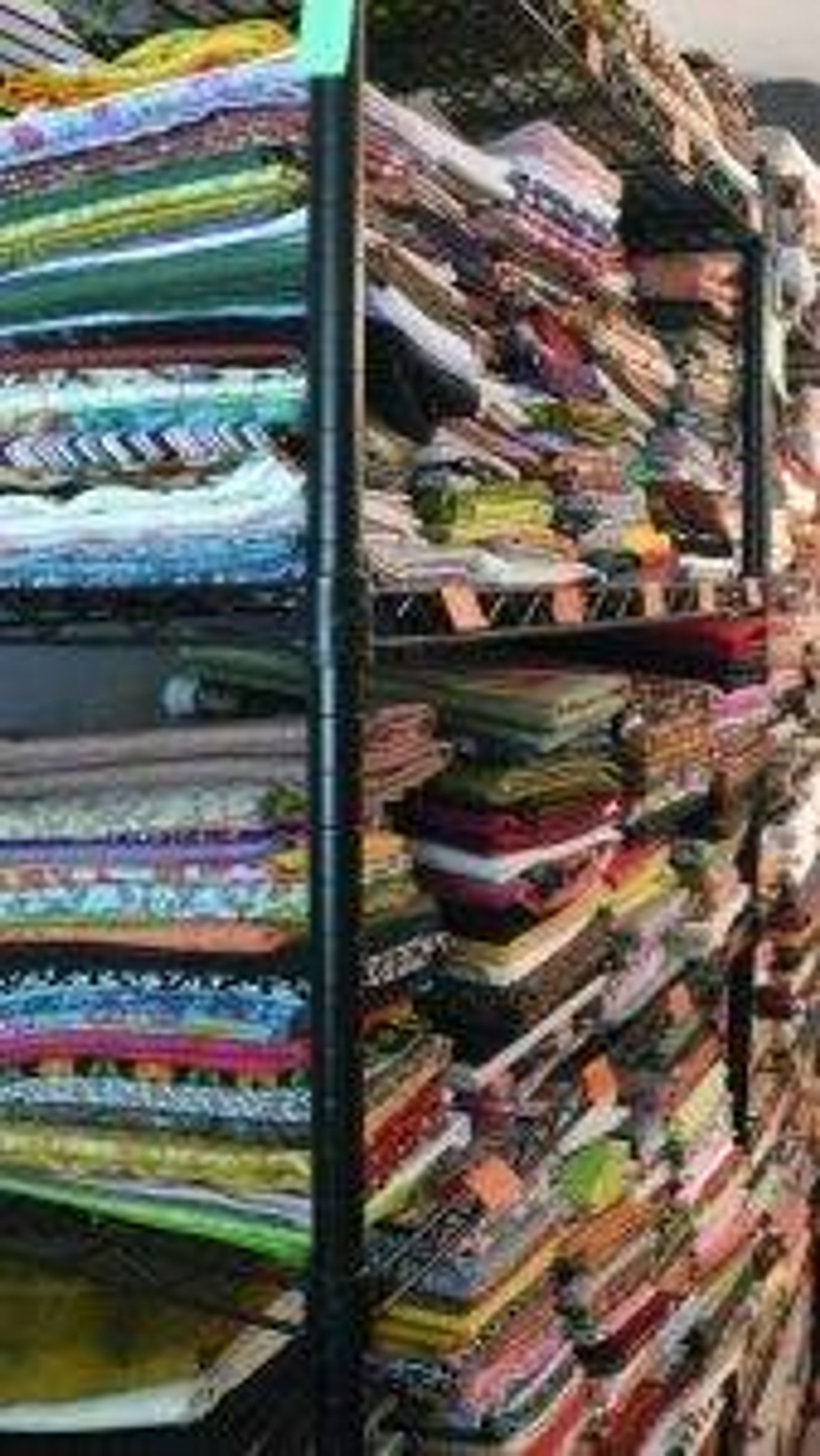 A shelf full of stacks and stacks of fabric.