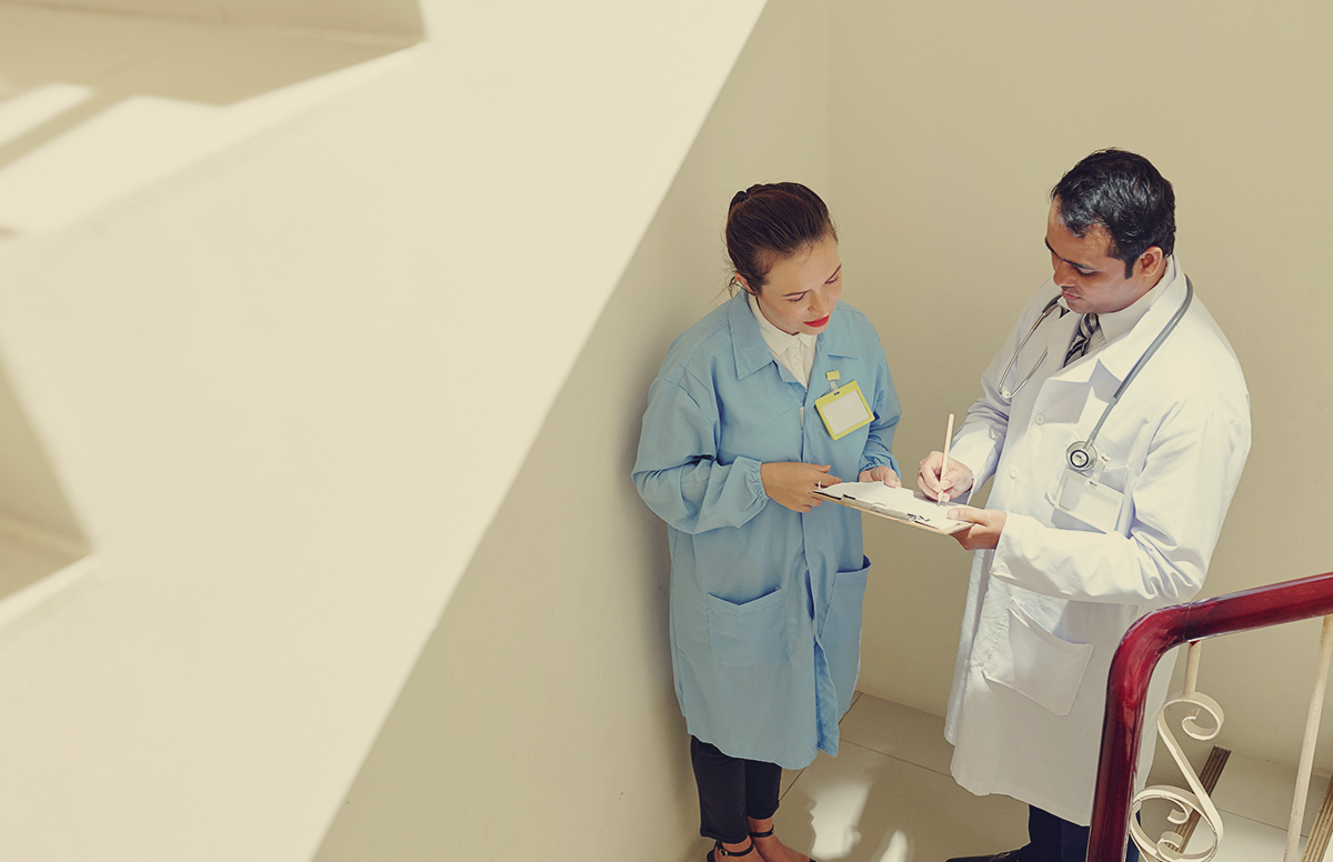 a doctor and other medical staff person discuss test results in a stairwell