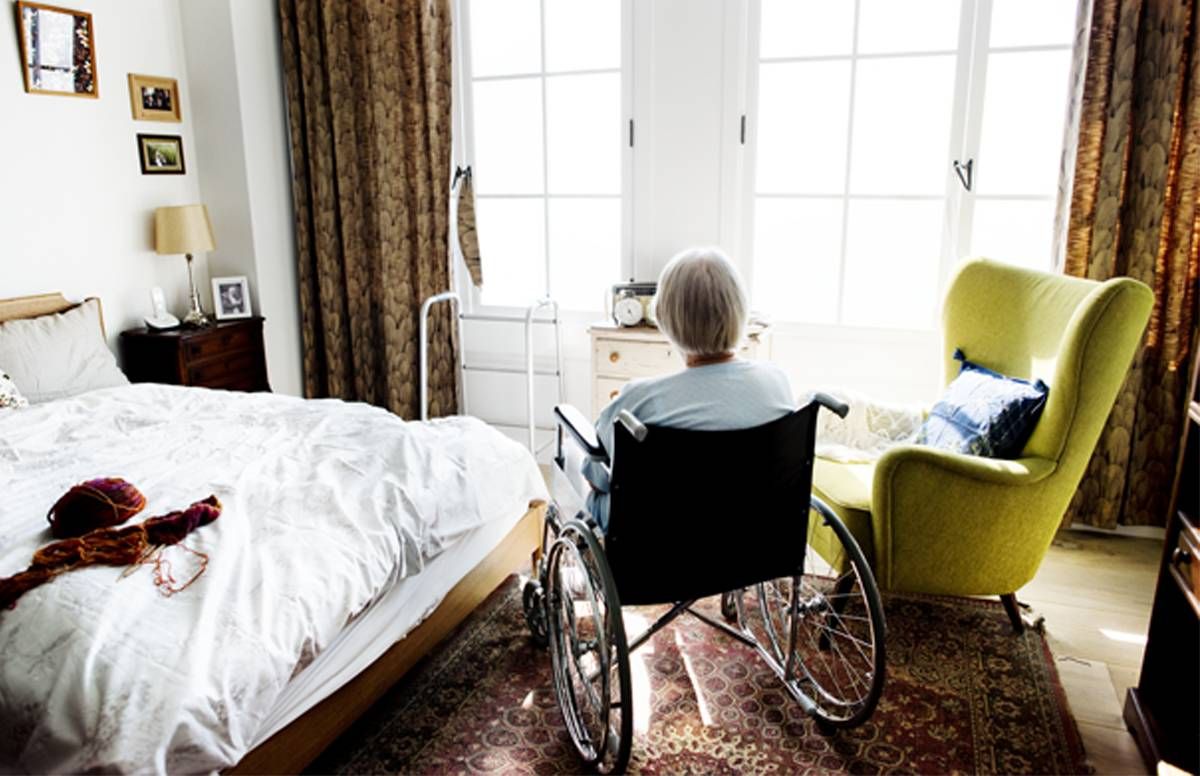 Woman in a wheelchair staring out of the window of her living area.