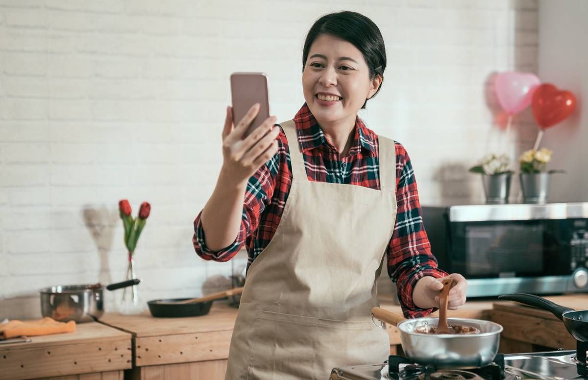 Woman cooking while watching a screen.