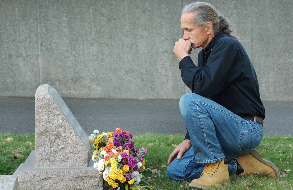 man kneeling alone at gravesite