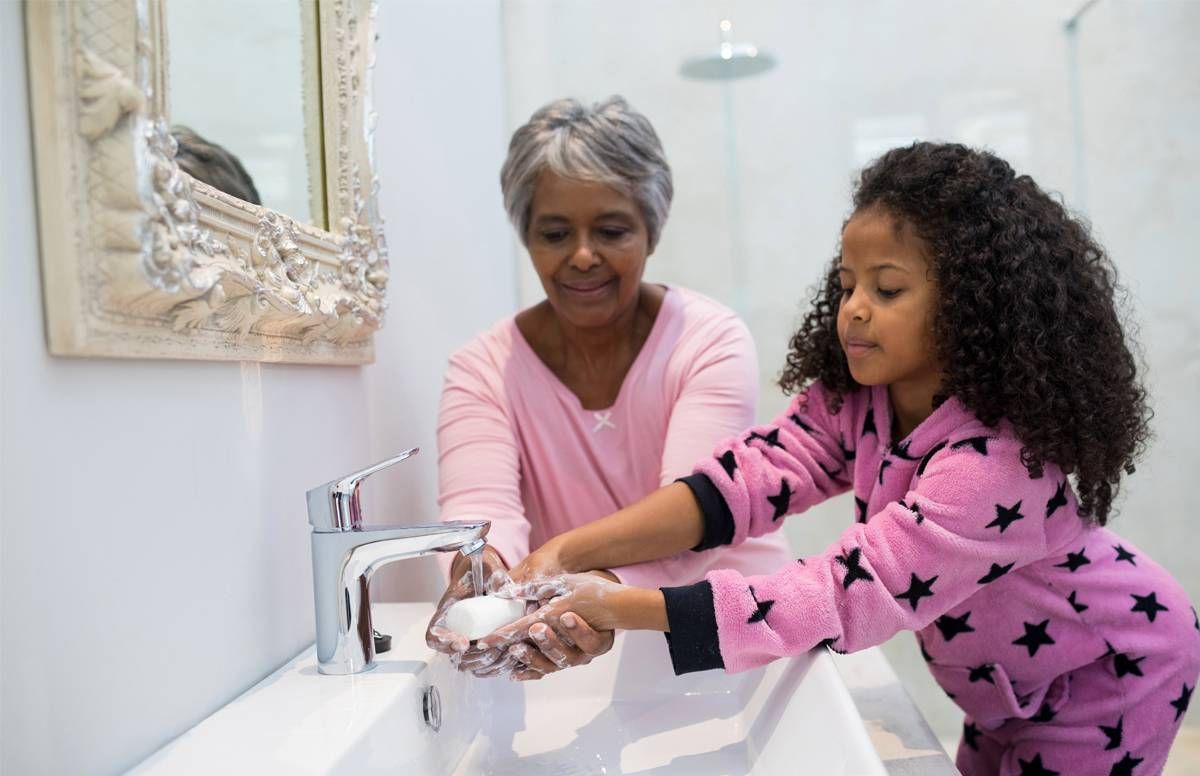 Grandmother helping granddaughter wash hands