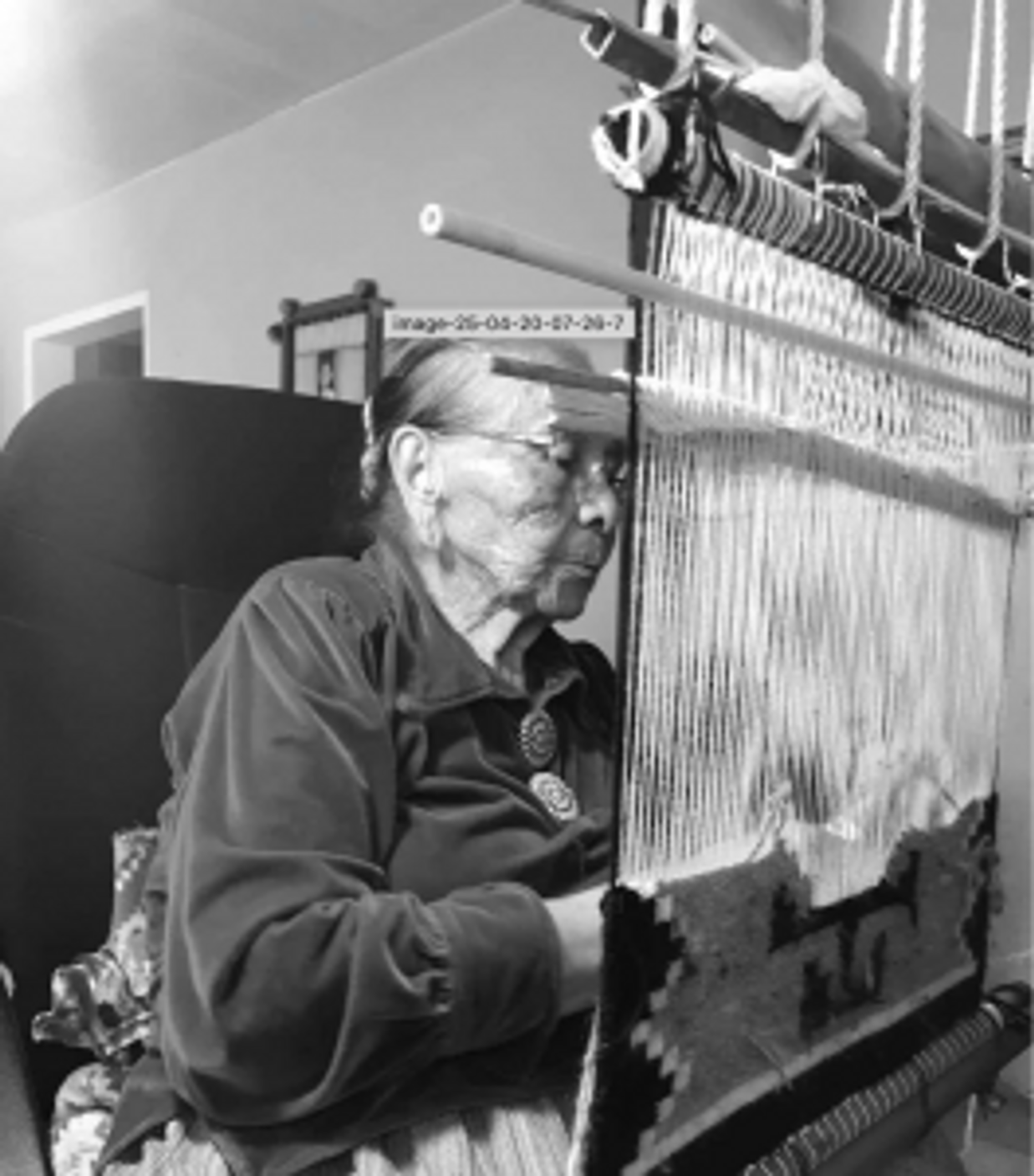 A photo of Bilagody weaving her last rug in 2017 before retiring from the craft