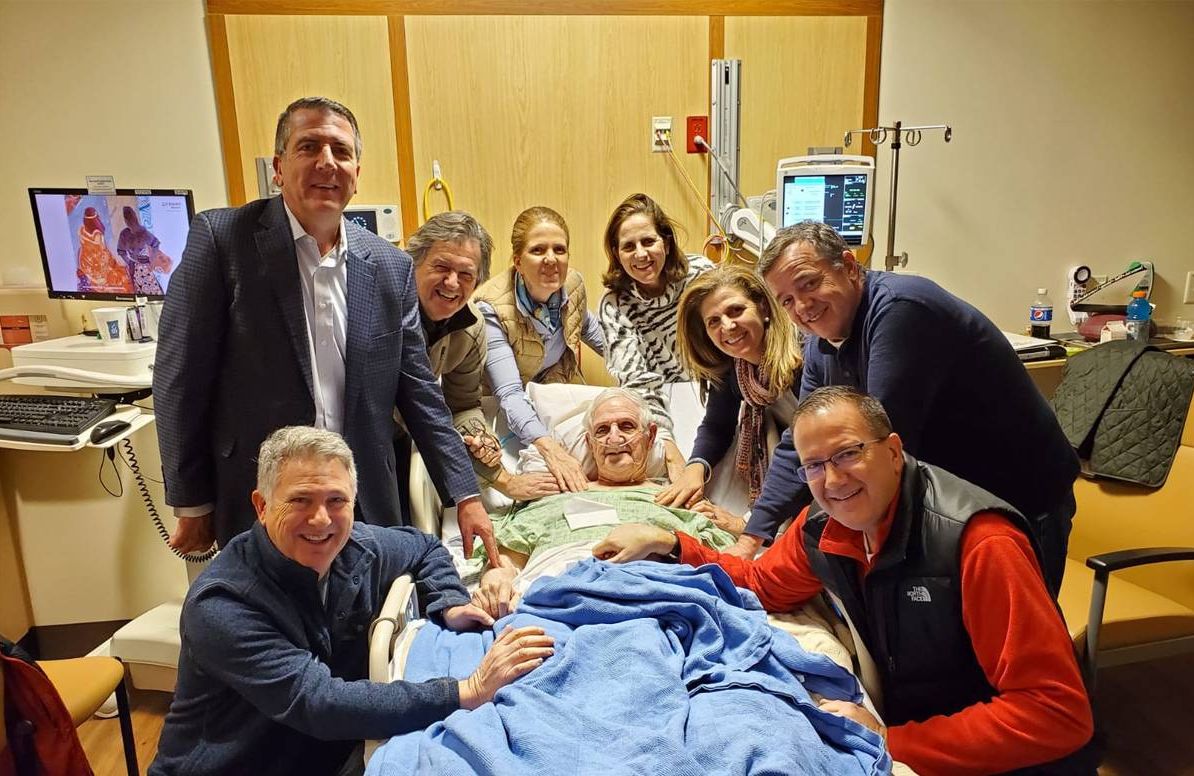 Brian Owen (third from left) and his siblings hired two private home health staff to care for their father (center) near Boston while he waited for a bed in a hospice