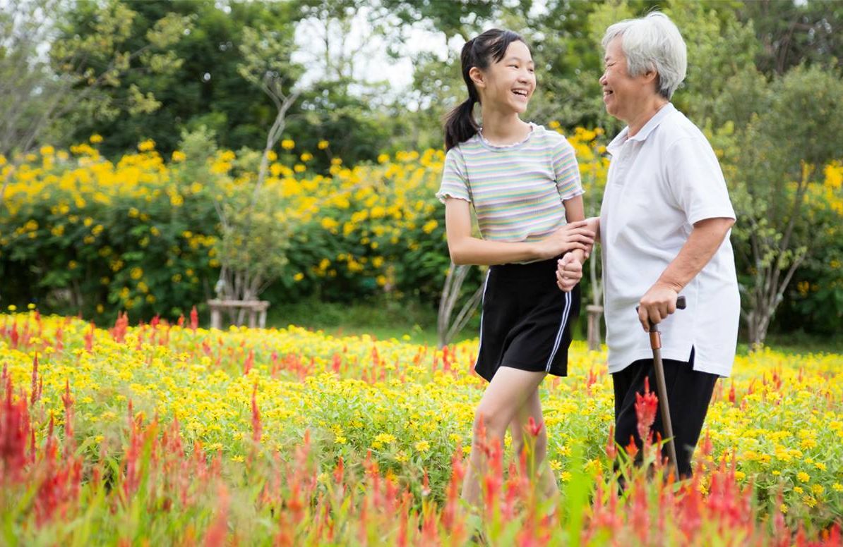 older woman and younger woman on a walk in a field of flowers