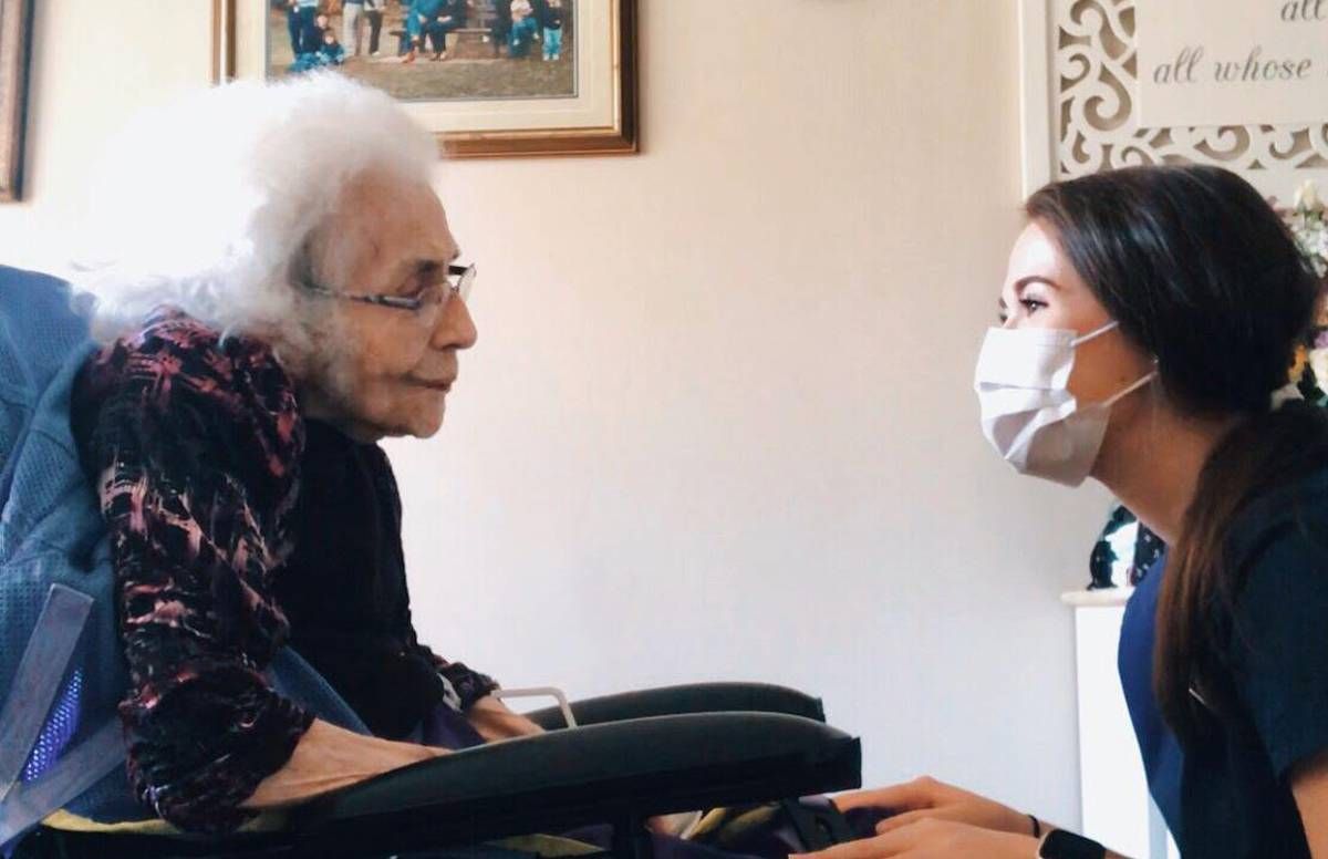 Rachel Stewart kneeling in front of her grandma in her wheelchair