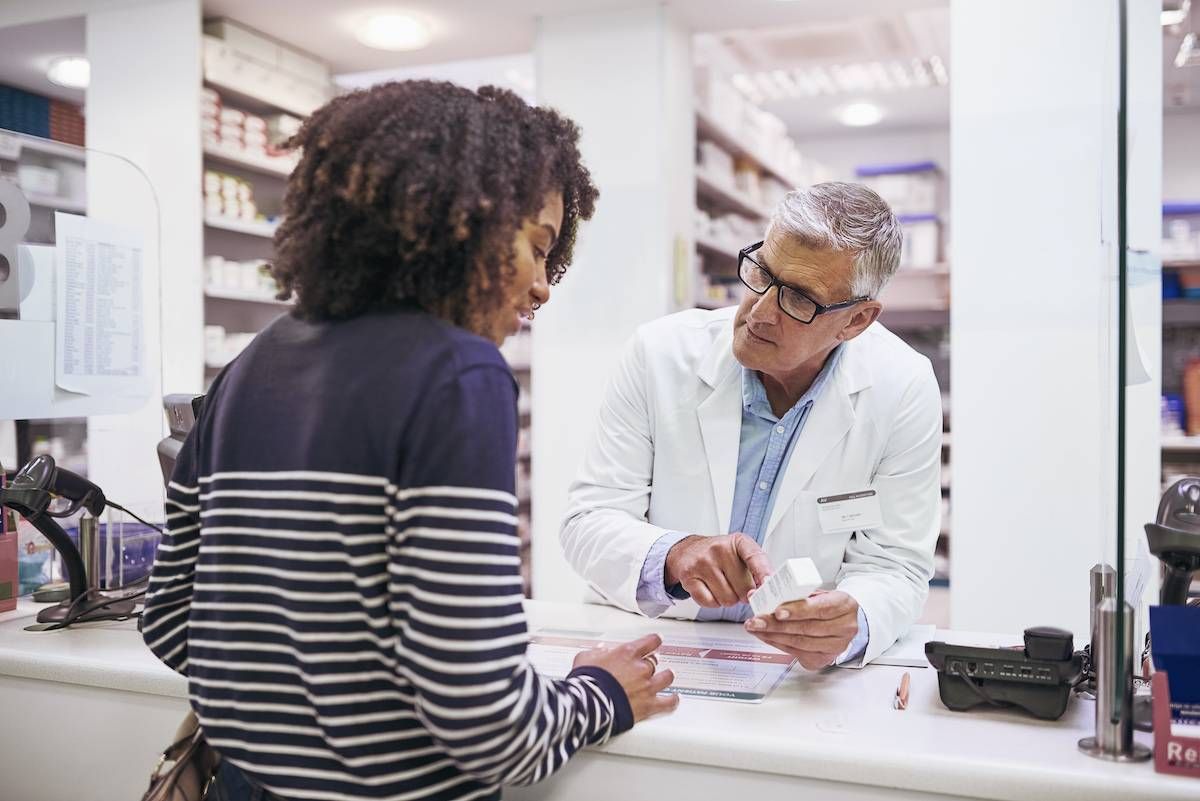 Shot of a dedicated mature male pharmacist giving a customer prescription meds over the counter