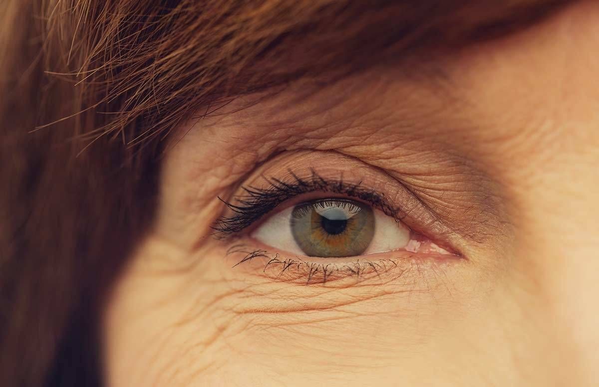 a woman with brunet hair is in frame, but only about 1/4 of her face. In the center is her hazel eye.