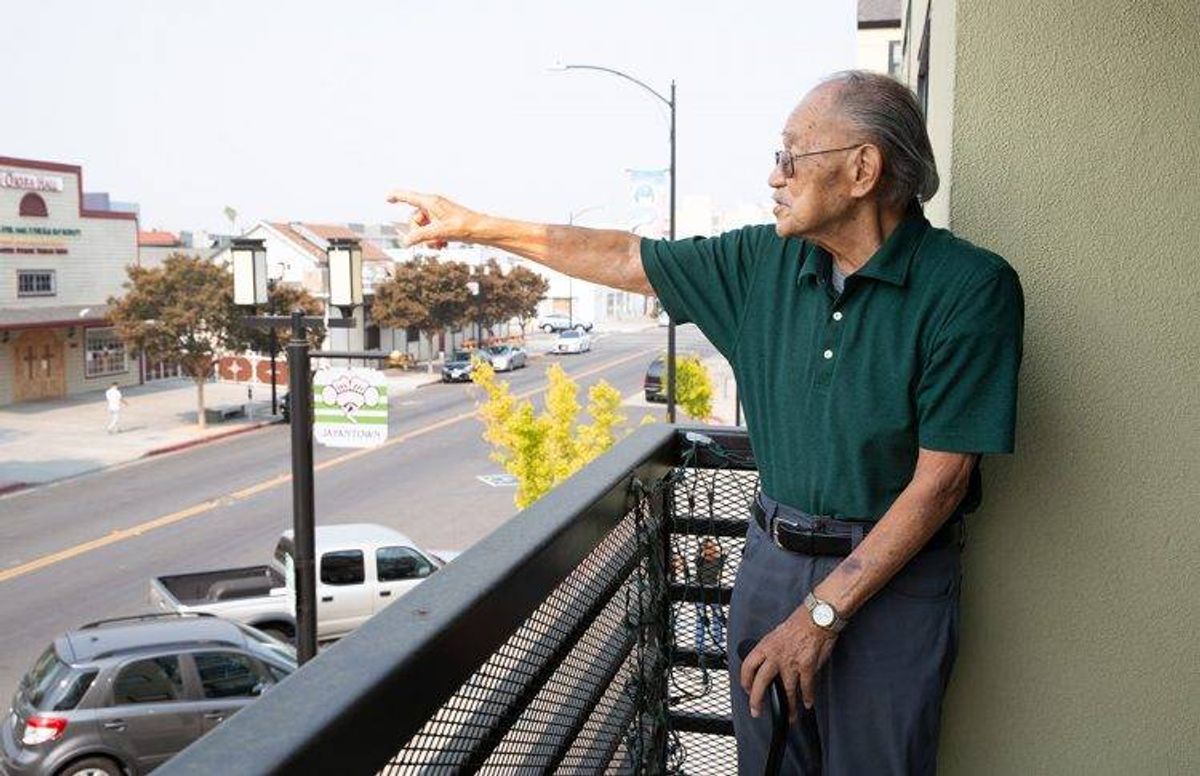 James Oka, 87, stands on his apartment balcony and points to the church he attended during childhood in San Jose’s Japantown.