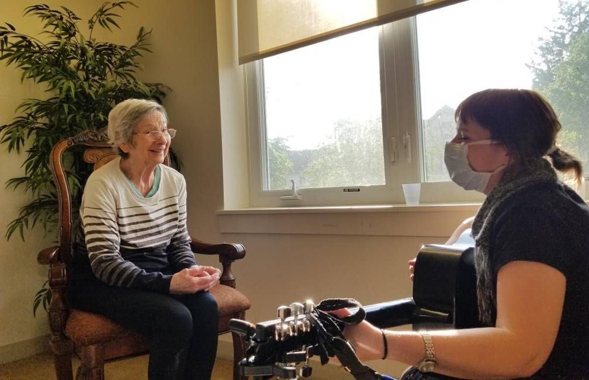 Music therapist Kimberly Williams plays guitar for patient Elaine Lego