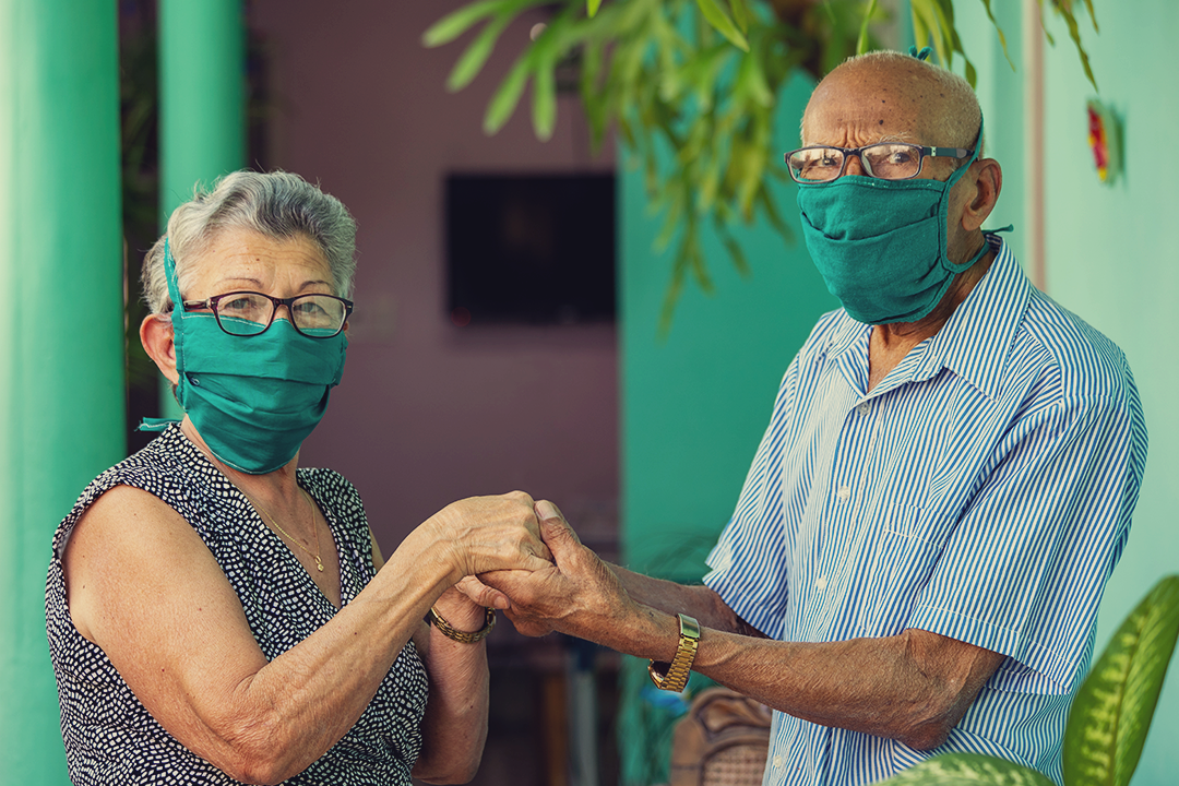 older couple holding hands while wearing masks