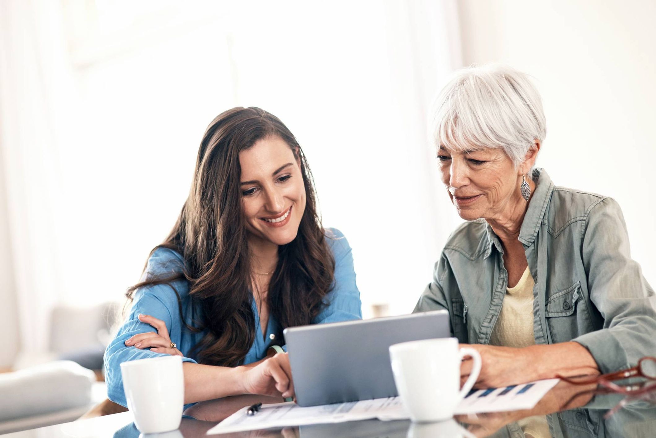 a younger woman sitting next to her older parent looking at a document