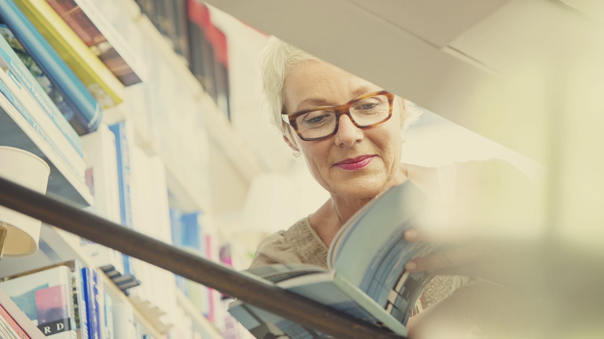 older woman smiling while reading a book