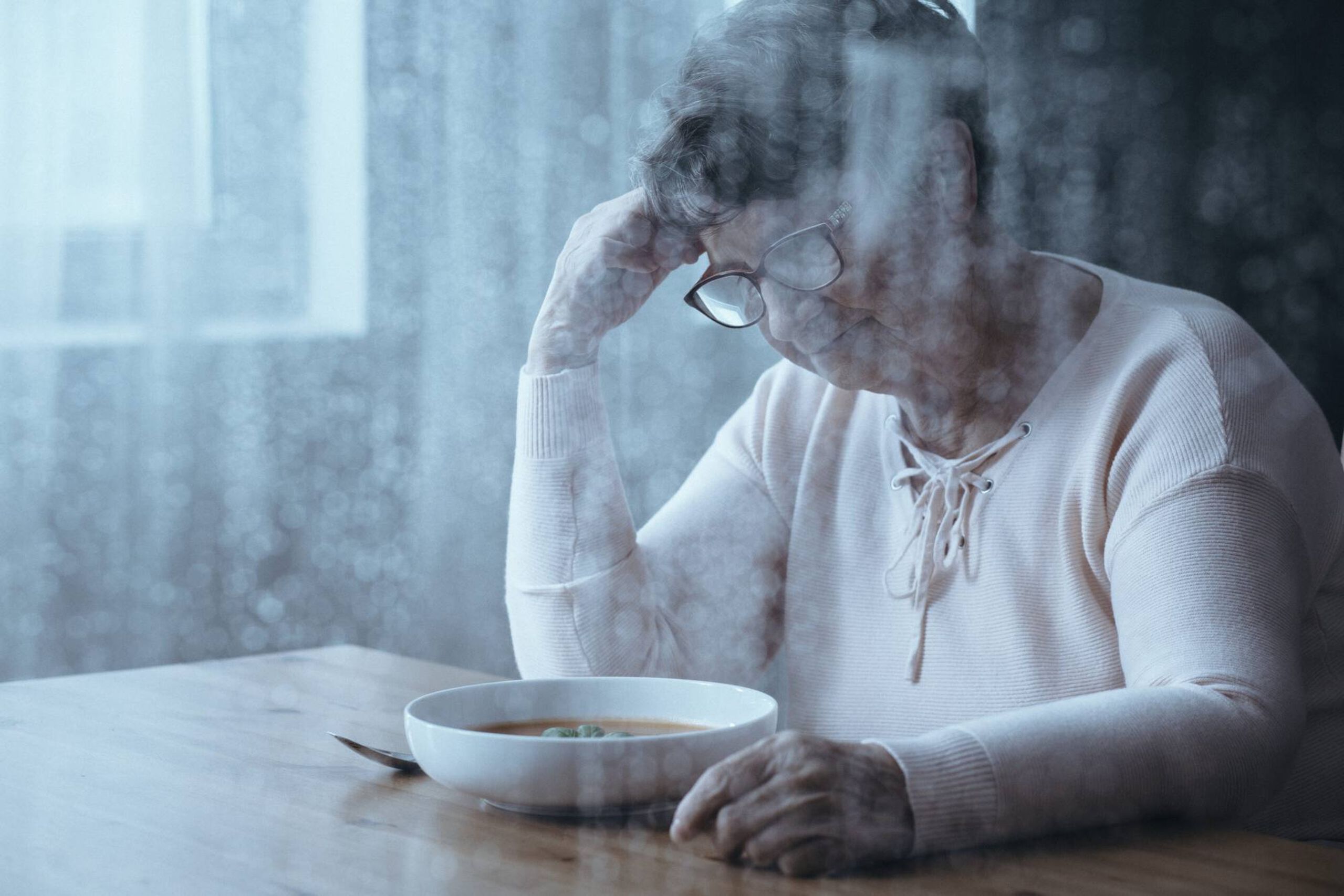 Woman at her kitchen table, sad, COVID-19 relief