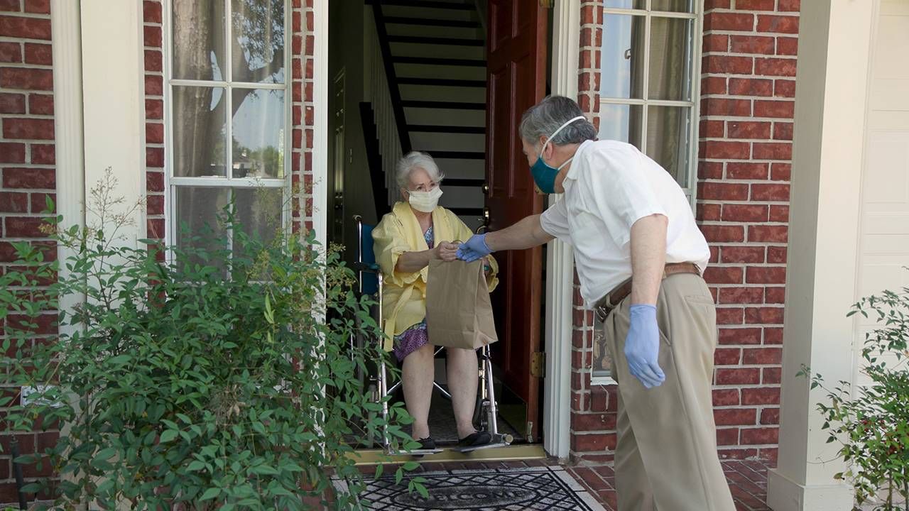 Older adult receiving groceries at her front door, COVID-19 vaccine